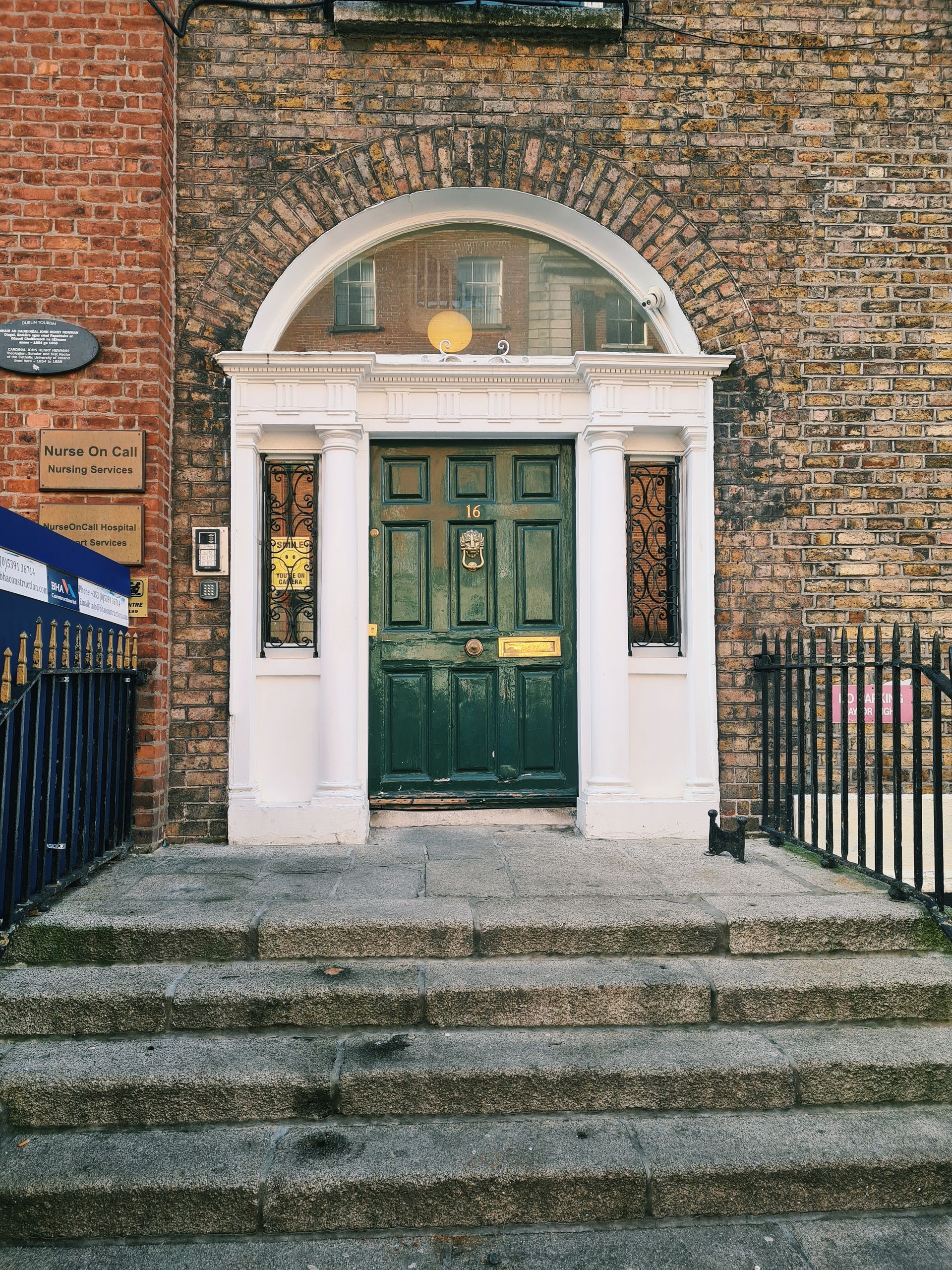 A Dublin Georgian doorway: forest-green door, ivory surround, and brass fittings on brick.